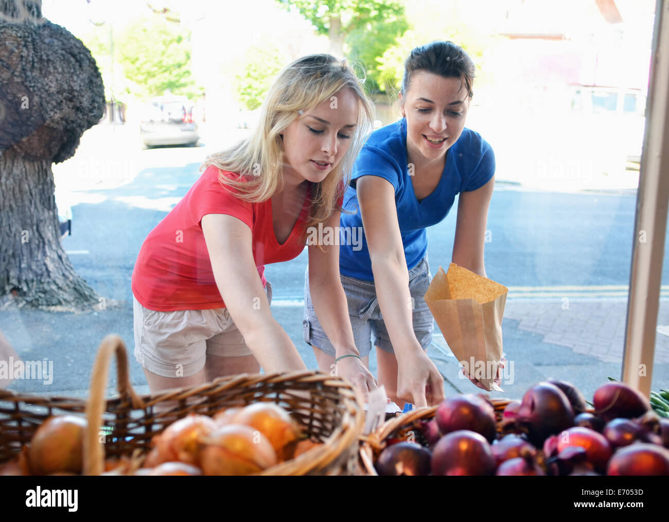 Due giovani donne la scelta di cibo a stallo del mercato Foto Stock