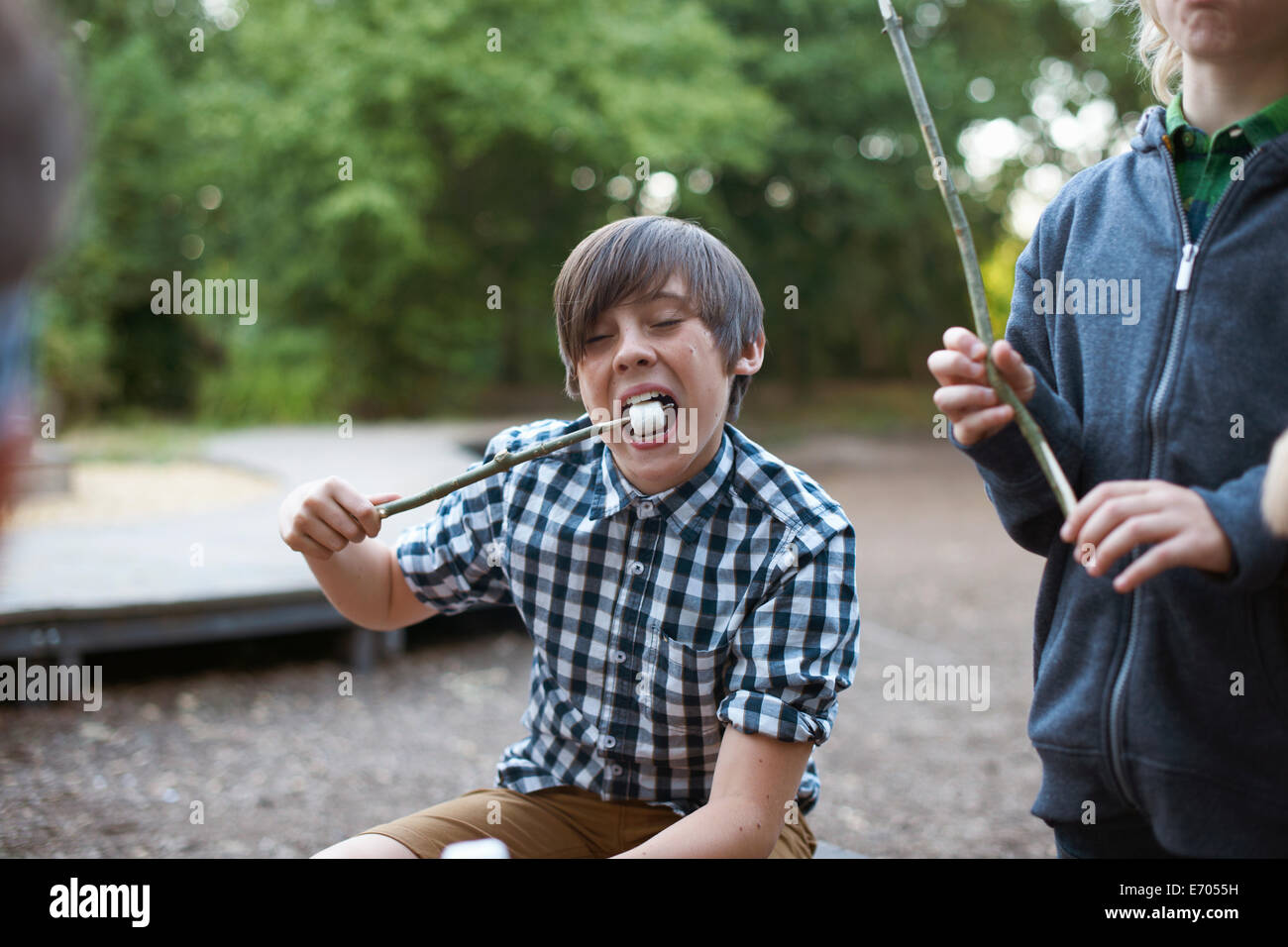 Ragazzo giovane mangiare tostato da marshmallow stick Foto Stock