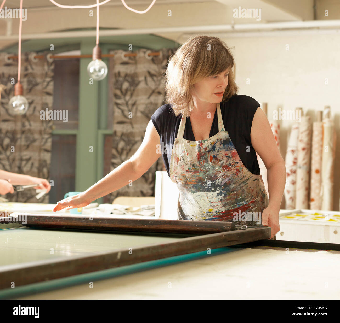 Donna a mano la stampa tessile in officina Foto Stock