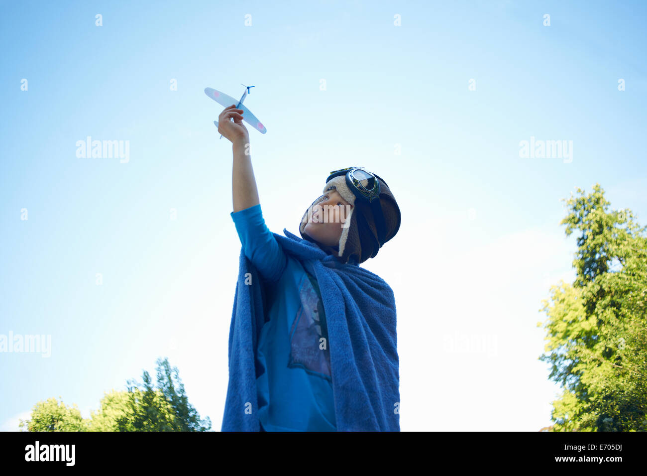 Giovane ragazzo in costume, giocando con aeroplano giocattolo Foto Stock