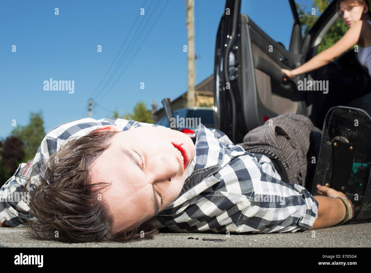 Giovane uomo colpita dalla vettura che giace sulla strada Foto Stock