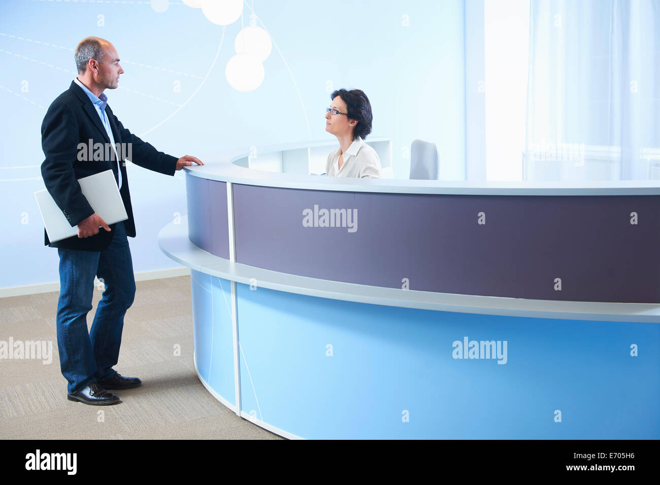 Adulto Uomo parlando a receptionist Foto Stock
