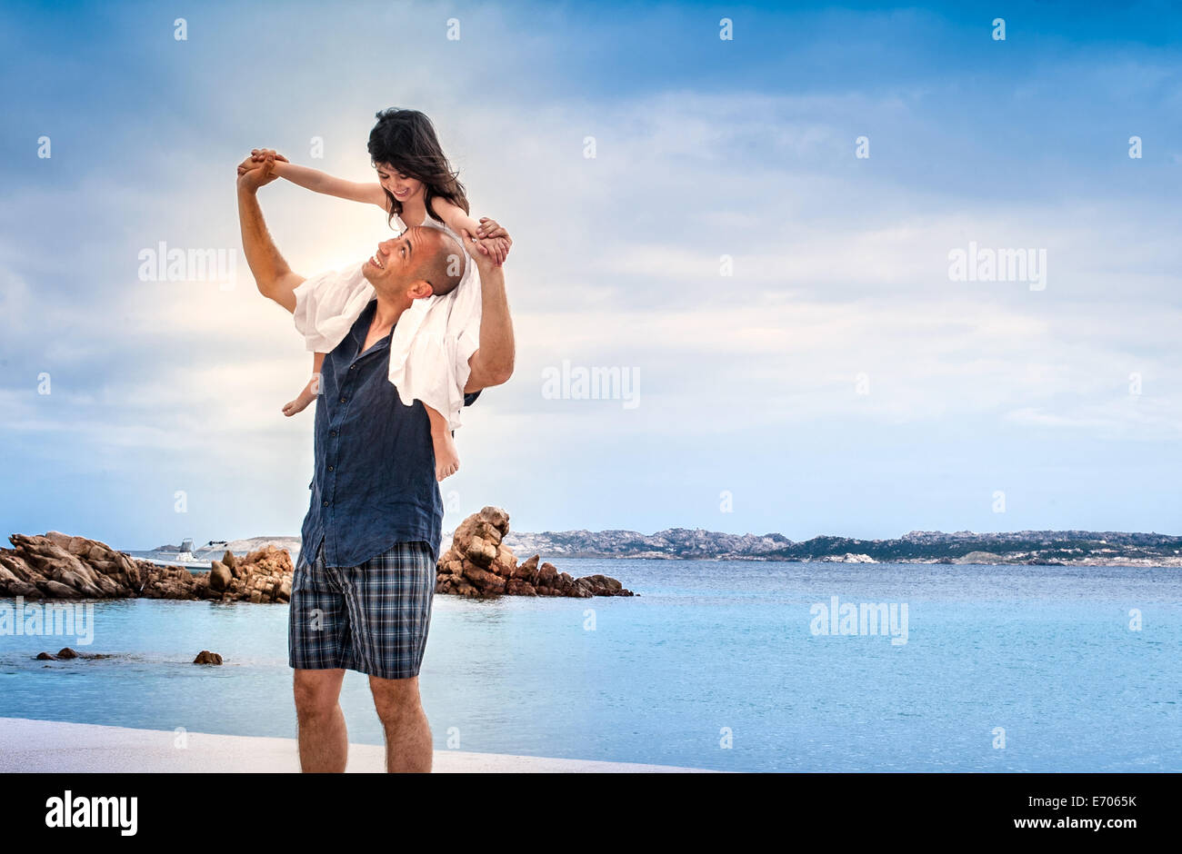 Metà uomo adulto dando figlia spalla corsa sulla spiaggia, La Maddalena, in Sardegna, Italia Foto Stock