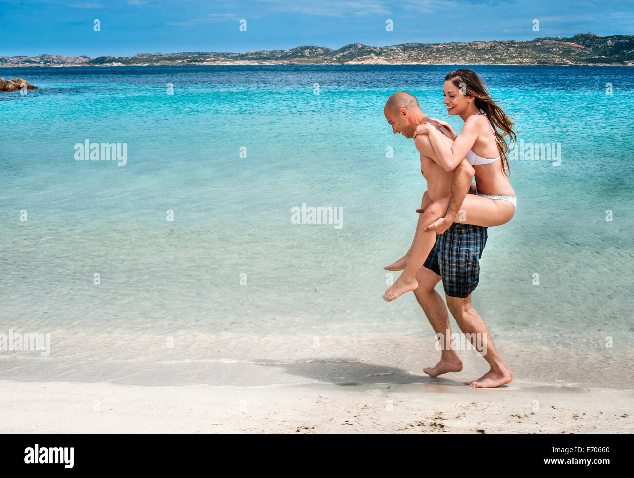 Metà uomo adulto dando ragazza piggy back sulla spiaggia, La Maddalena, in Sardegna, Italia Foto Stock