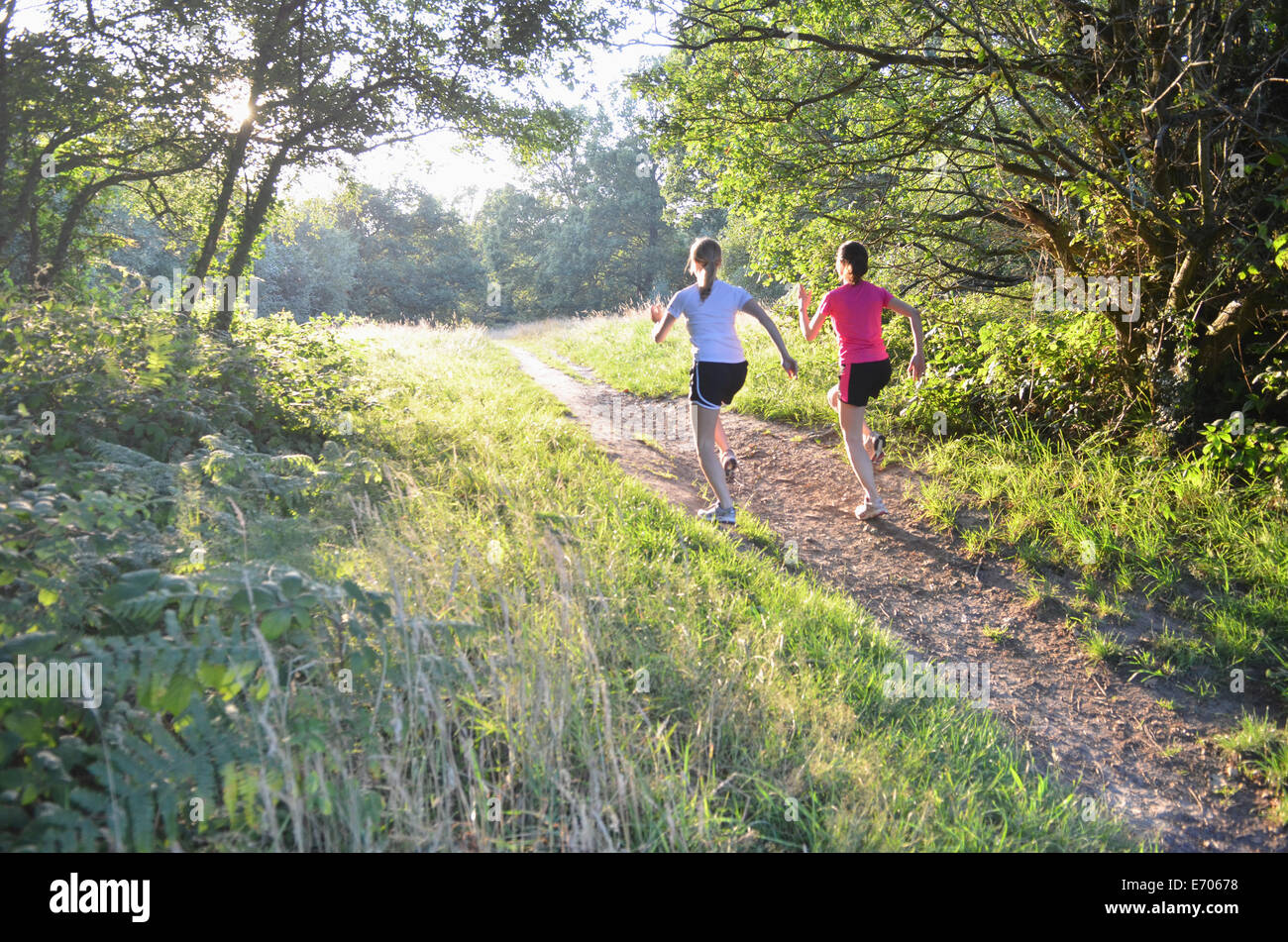 Due giovani runner donna corre su pista forestale in mattinata Foto Stock