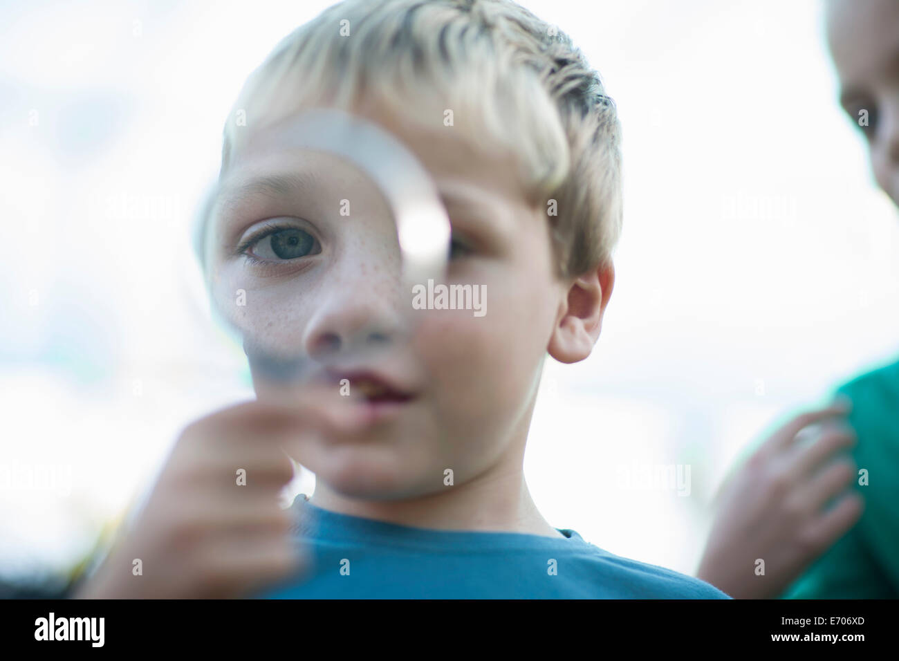 Ritratto di ragazzo holding lente di ingrandimento nella parte anteriore dell'occhio Foto Stock