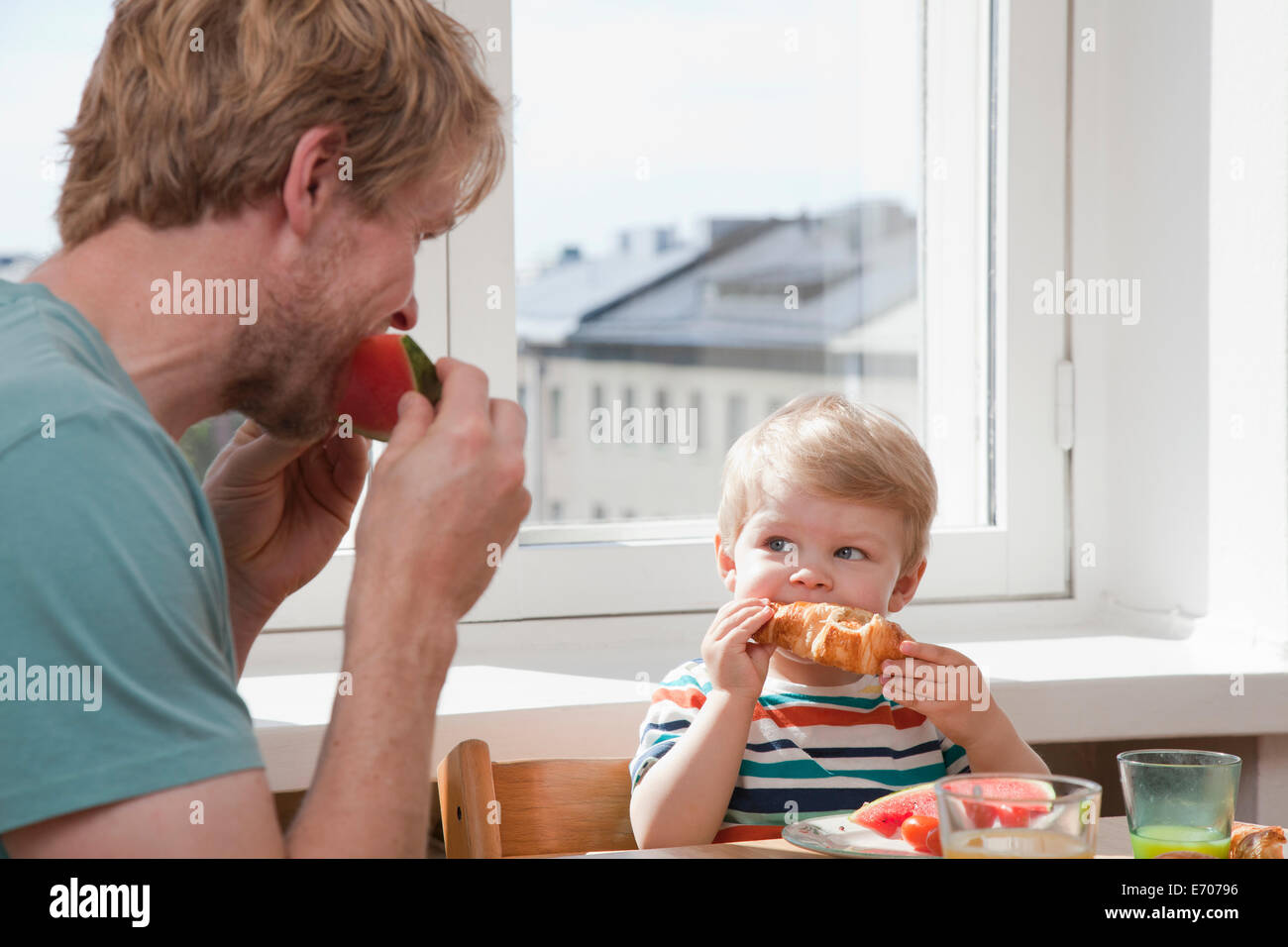Padre e figlio dei bimbi di mangiare la prima colazione al tavolo della cucina Foto Stock