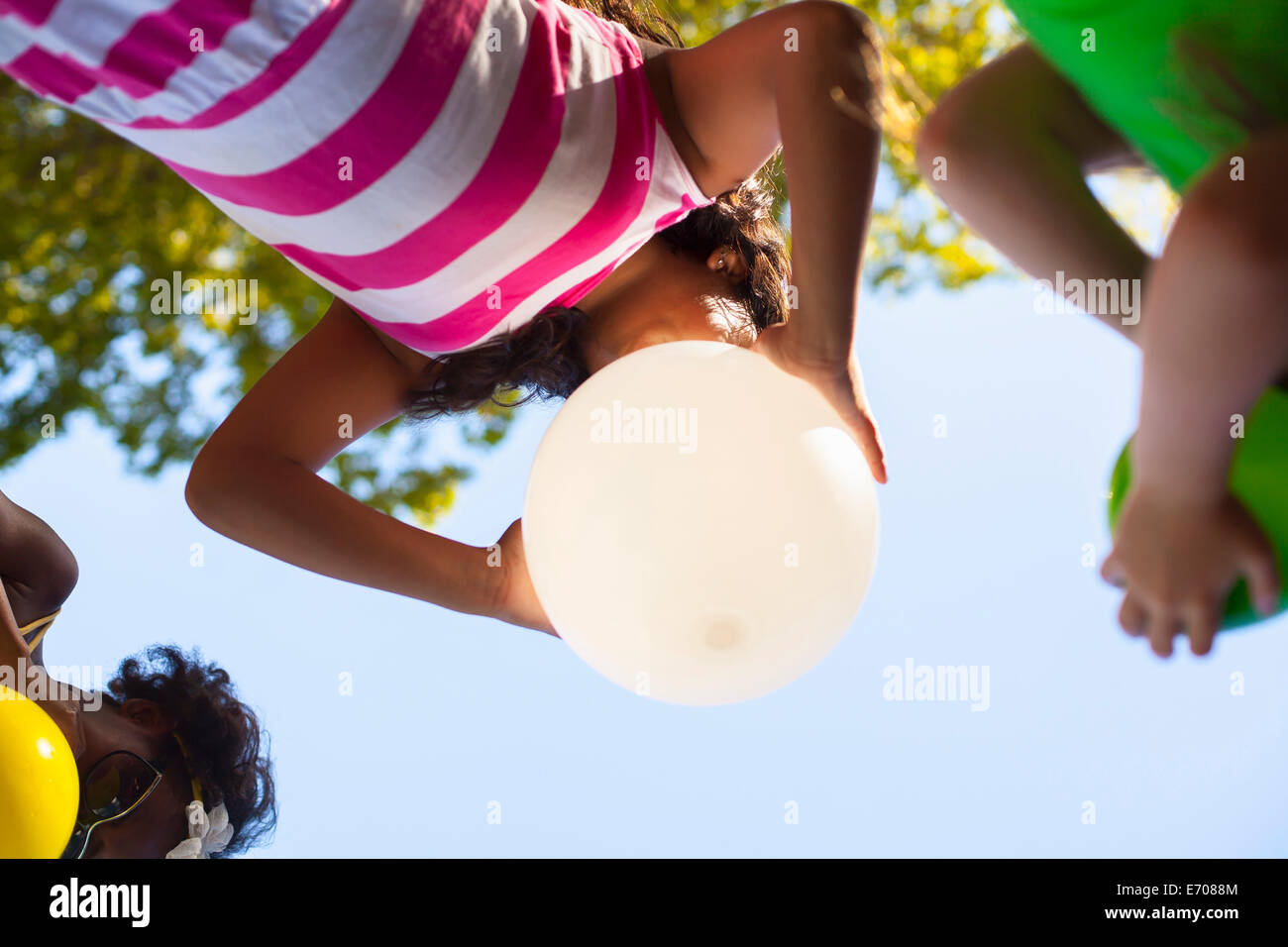 Basso angolo vista di tre ragazze gonfiare palloncini in giardino Foto Stock