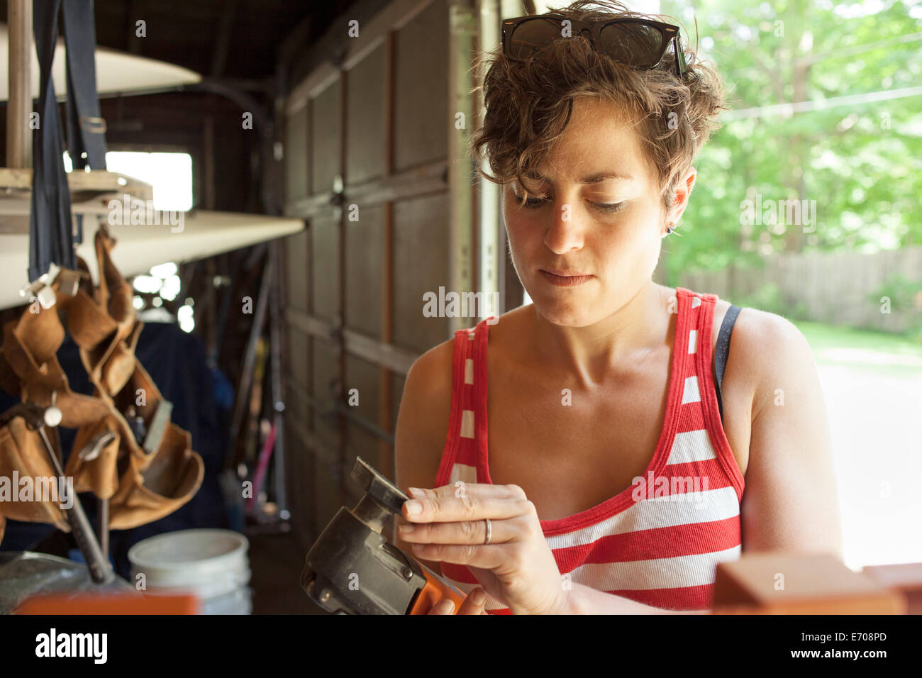 Metà donna adulta levigatrice a preparare per il restauro di mobili in garage Foto Stock