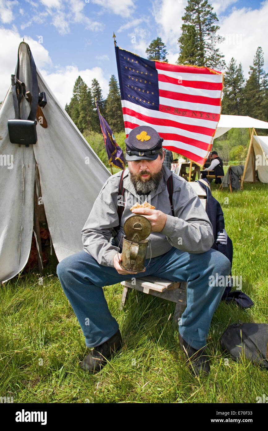 Un Unior soldato ha un po' di hard tack ad una guerra civile rievocazione storica tra nord e sud del soldato detenute nel fiume Metolius centrali di Oregon. Foto Stock