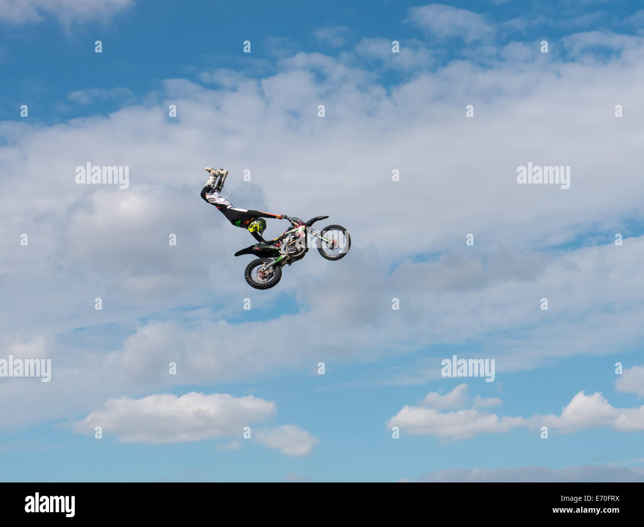 FMX moto rider completando le acrobazie sullo sfondo di un cielo blu con nuvole Foto Stock