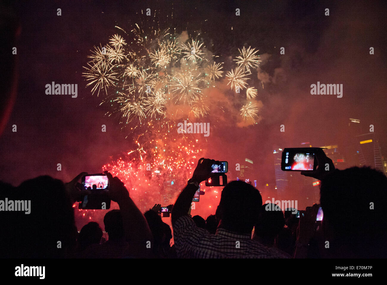 Festaioli catturare il Giorno di Indipendenza fuochi d'artificio celebrazioni nei loro telefoni cellulari e tablet presso la Baia di Singapore Foto Stock
