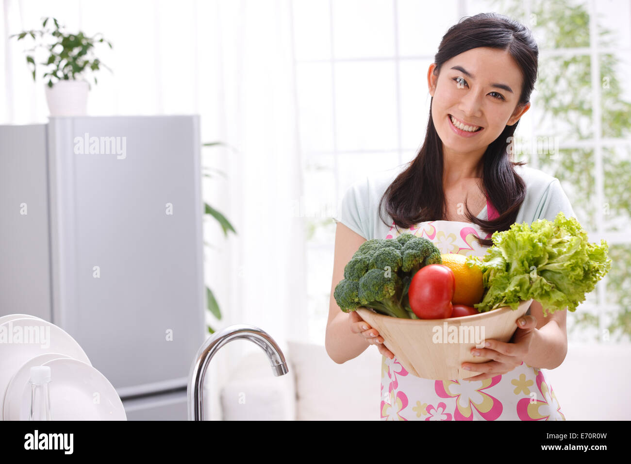 Giovane donna tenendo la verdura in cucina Foto Stock