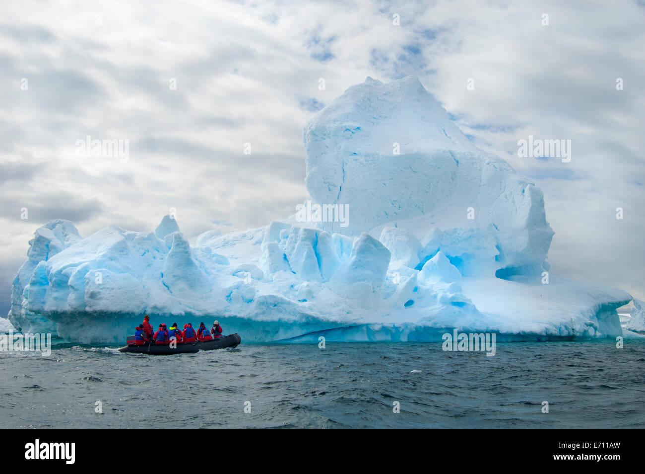 Le persone in piccoli inflatible zodiac barche di nervatura passando iceberg e ice floes intorno piccole isole dell'Antartico. Foto Stock