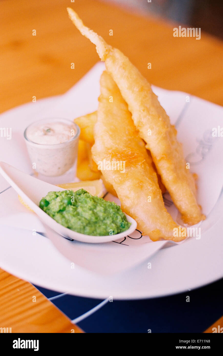 Cibo tradizionale, martoriato fritto pesce e patatine, con piselli fiacco e tartare di salsa su una piastra. Foto Stock