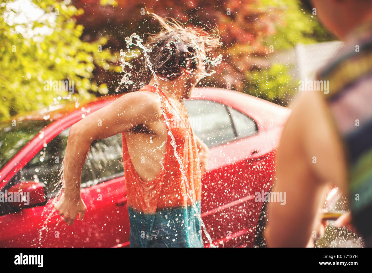 Giovane uomo che viene spruzzato con acqua Foto Stock