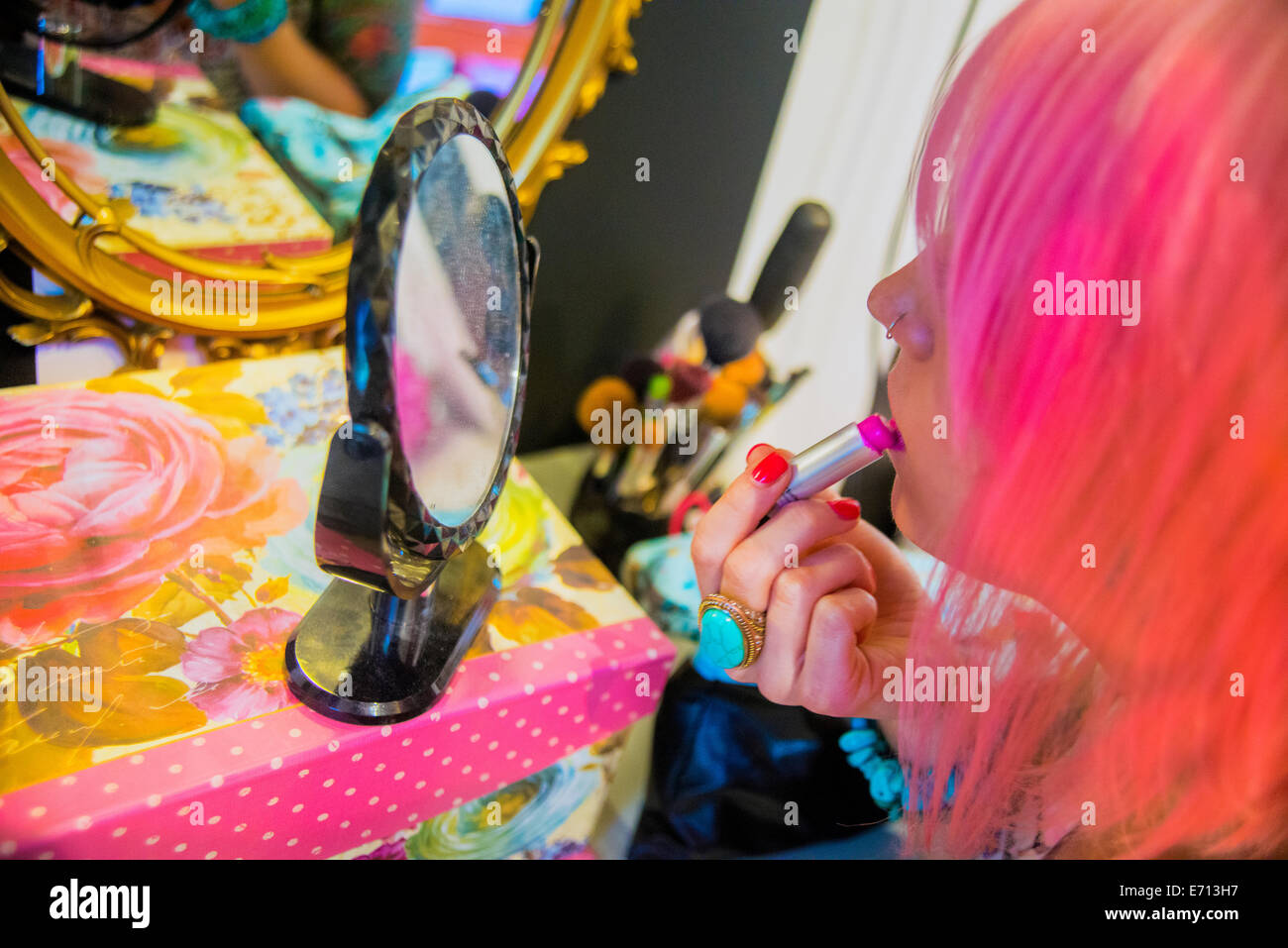 Giovane donna con capelli rosa mettendo in rosa rossetto Foto Stock