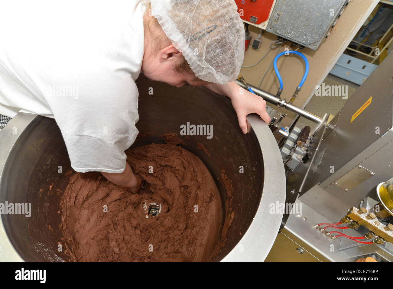 Germania, Sassonia-Anhalt, donna di agitazione la miscela di cioccolato in un bollitore in una fabbrica di cottura Foto Stock