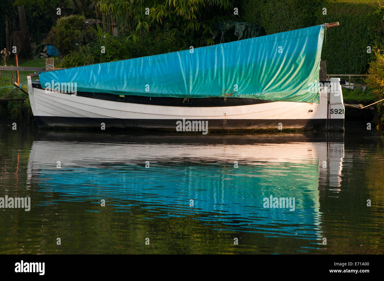 Piccola barca a vela ormeggiata coperto sulla banca del fiume Foto Stock