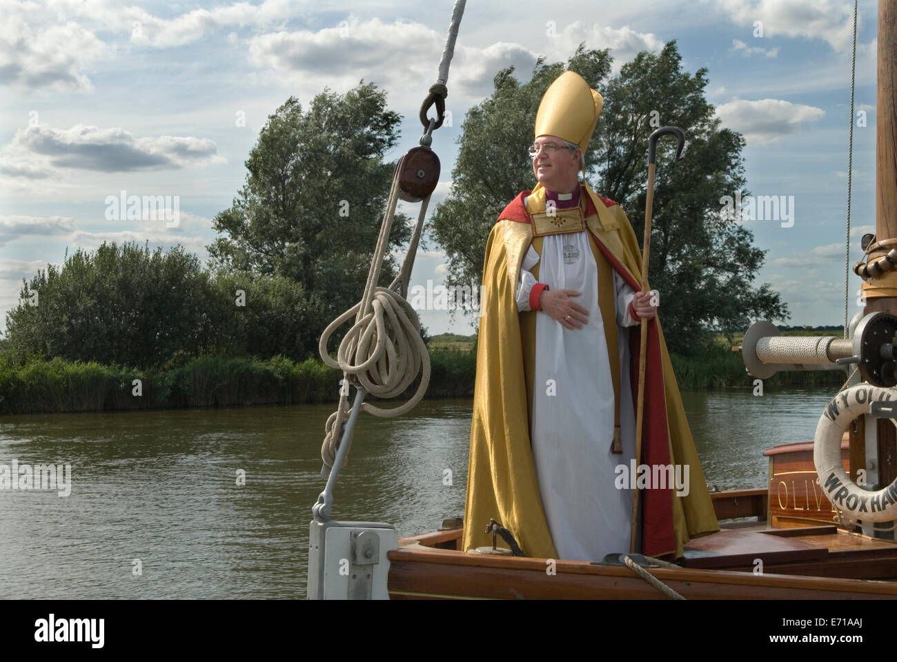 Norfolk Broads barca tradizionale chiamata Wherry. Il vescovo di Norwich, il reverendo Graham James, arriva all'abbazia di St Benets, vicino a Ludham, Norfolk orientale. Arriva su un Wherry che sale sul fiume Bure per condurre il servizio annuale, la prima domenica di agosto. 2014 2010 UK HOMER SYKES Foto Stock