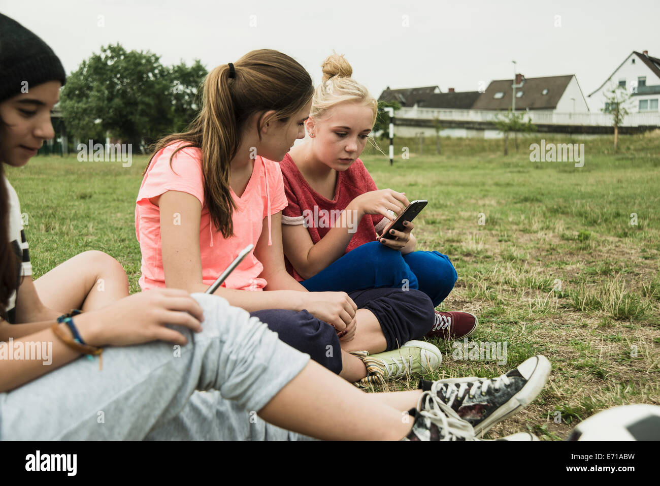 Quattro adolescenti di sesso femminile amici seduti sul campo da calcio  utilizzando il proprio smartphone Foto stock - Alamy