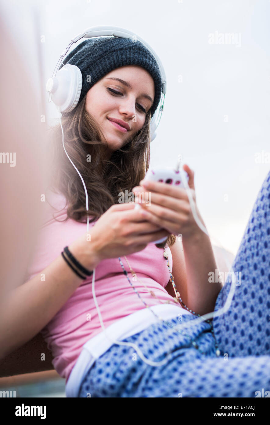 Ritratto di sorridente ragazza adolescente tenendo lo smartphone l'ascolto della musica con le cuffie Foto Stock