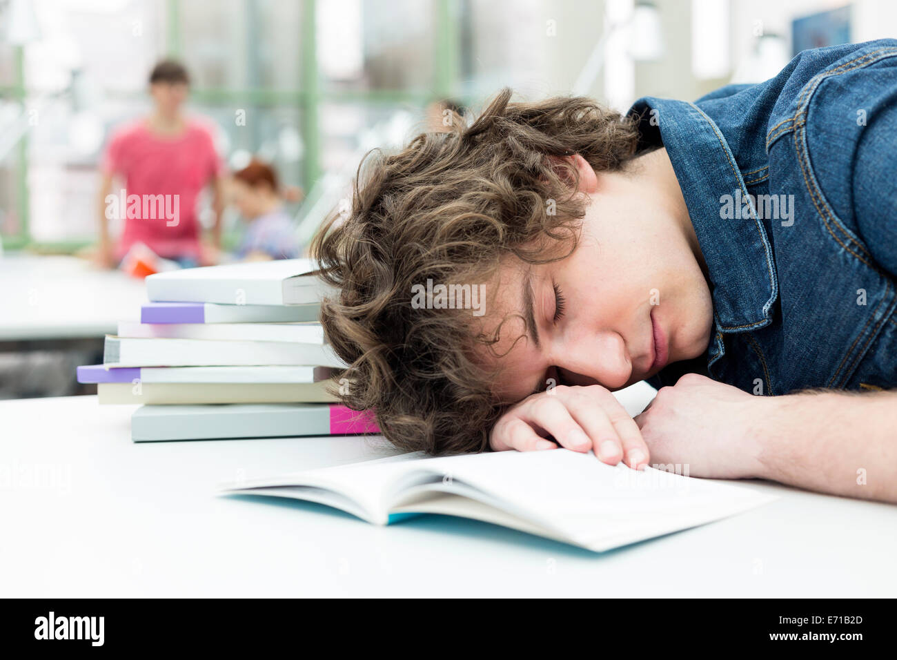 Esaurito studente dormire in una biblioteca universitaria Foto Stock