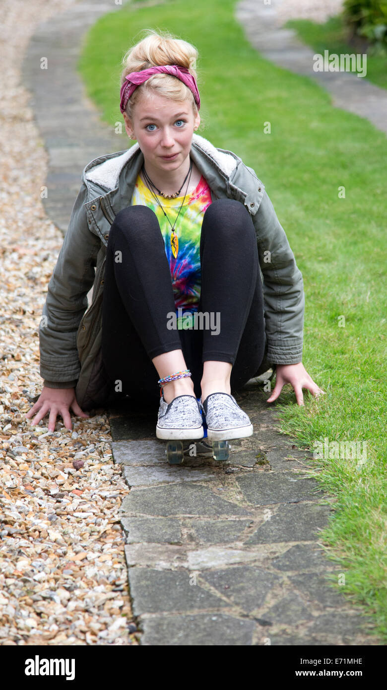 Ragazza seduta su skateboard skateboard su un percorso da giardino Foto Stock