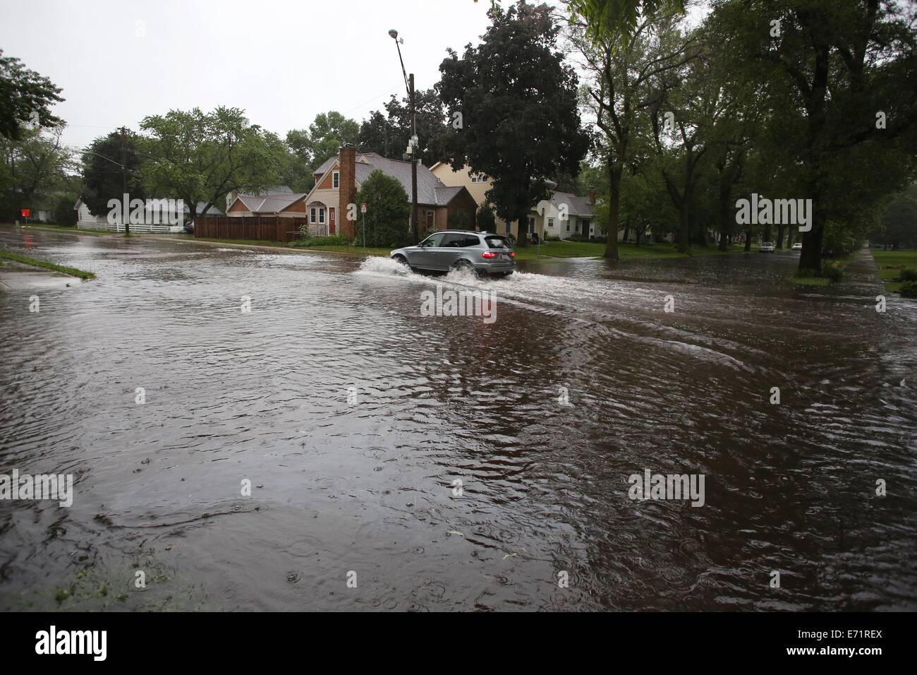 Una unità di auto attraverso l'acqua alta in un invaso street a Minneapolis, Minnesota. Foto Stock