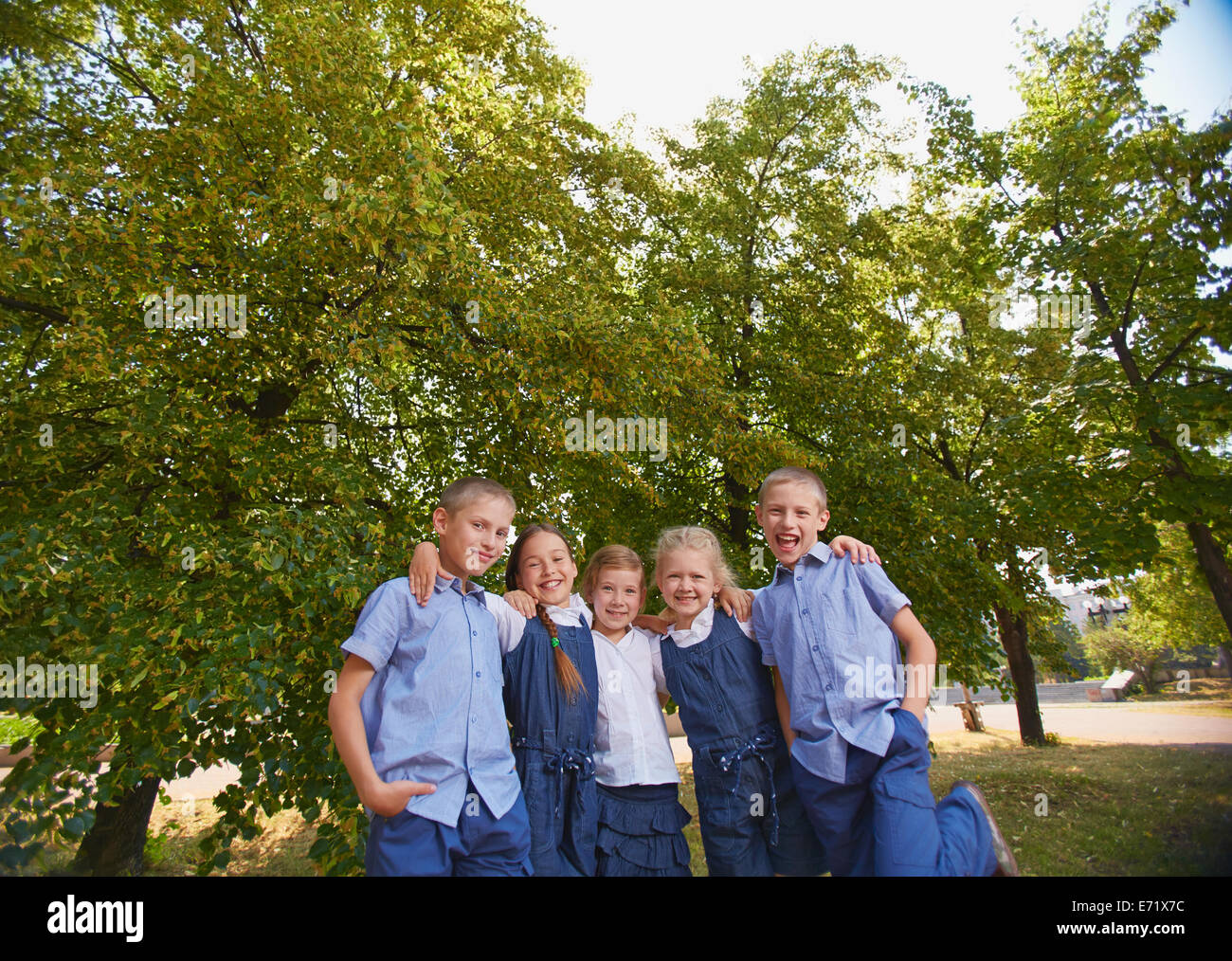 Gruppo di felice schoolkids guardando la fotocamera in posizione di parcheggio Foto Stock