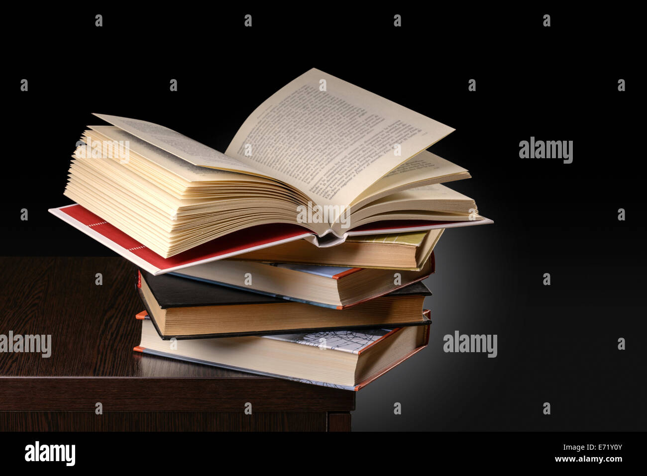 Una pila di libri con uno aperto sulla parte superiore, sul banco di uno studente alla sera Foto Stock Una pila di libri con uno aperto sulla parte superiore, sul banco di uno studente alla sera Foto Stock