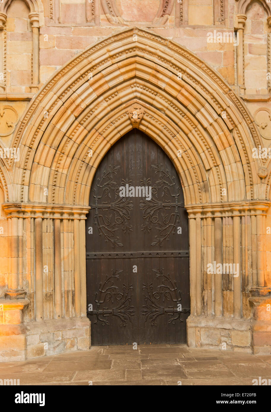 Ad arco porta in legno con enorme e spettacolare cerniere decorative circondato da ornati in archi di pietra nello storico Bolton priory chiesa Inghilterra Foto Stock