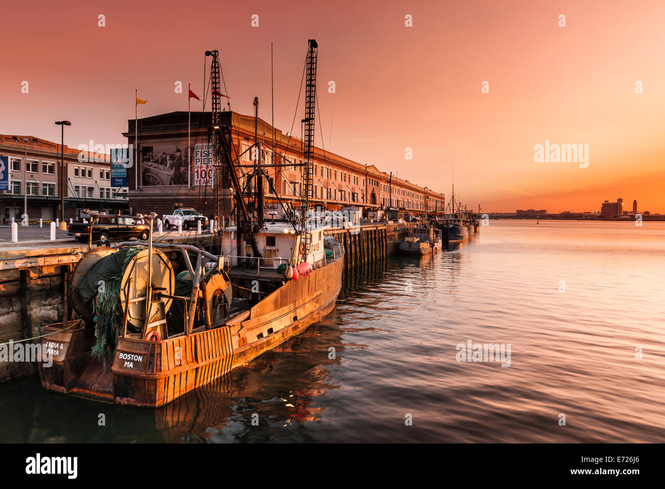 Il sole sorge su Logan International Airport, l'illuminazione delle barche da pesca ormeggiate lungo il molo del pesce nel quartiere portuale Foto Stock
