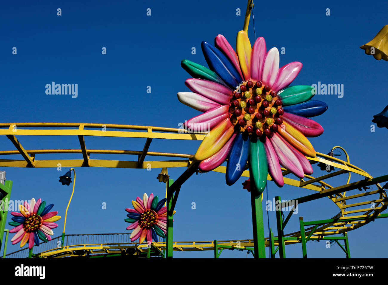 Una luminosa colorata di fiori in plastica è parte di un mini roller coaster in un luna park Foto Stock