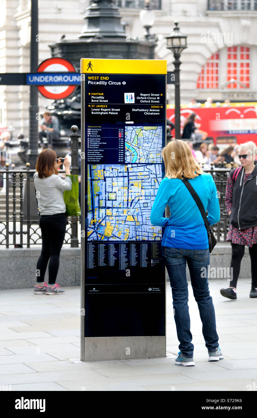 Londra, Inghilterra, Regno Unito. Giovane donna in Piccadilly Circus guardando una strada turistica mappa Foto Stock