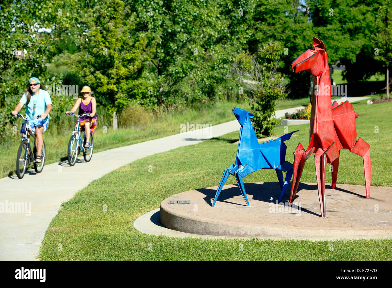 " Il rosso e il blu Pony' scultura, da Kevin Box, e ciclisti sul sentiero, Benson Sculpture Garden, Loveland, Colorado, STATI UNITI D'AMERICA Foto Stock