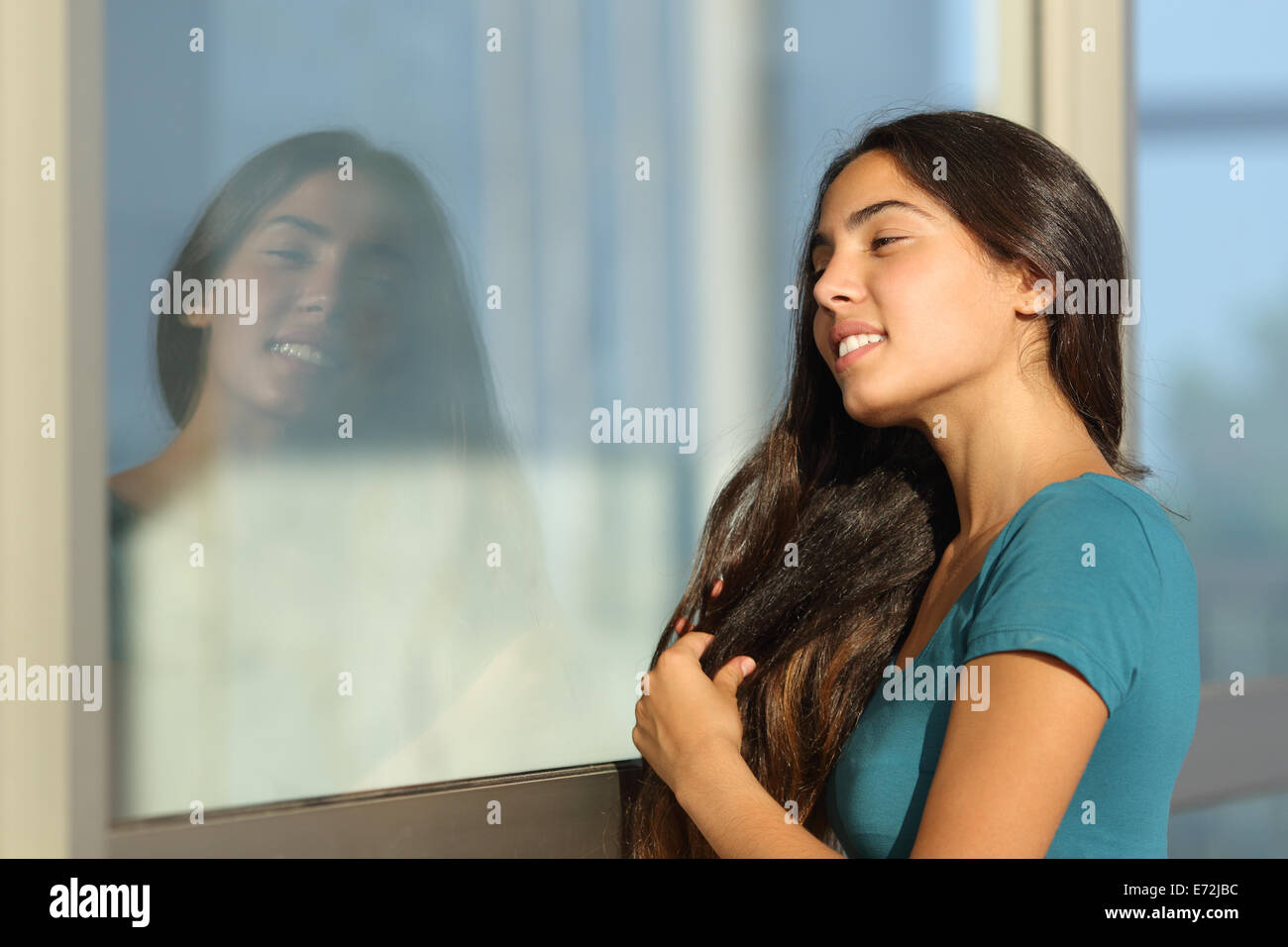 Flirty girl teen pettinare i capelli usando una finestra come uno specchio per esterno in strada Foto Stock