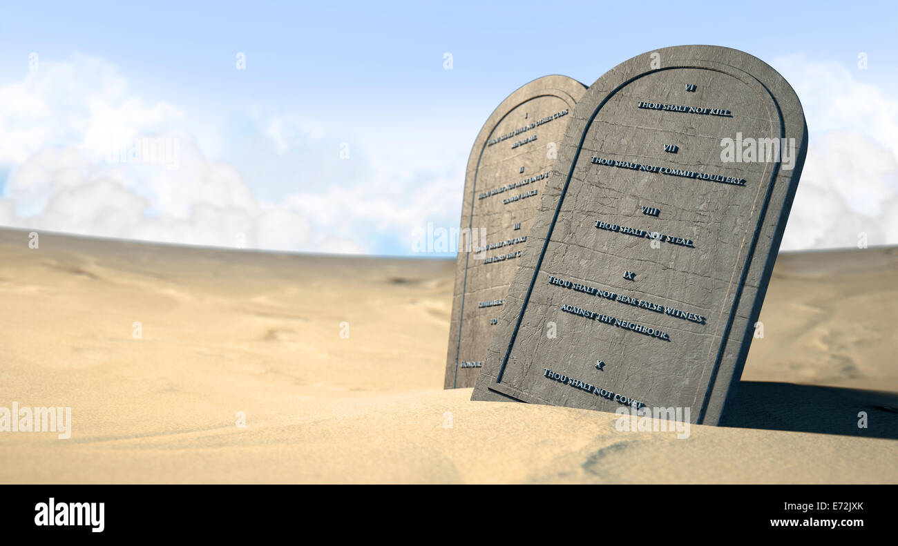 Due tavolette di pietra con i dieci comandamenti incisi su di loro in piedi in marrone sabbia del deserto di fronte un cielo blu Foto Stock