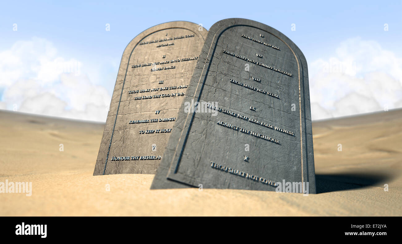 Due tavolette di pietra con i dieci comandamenti incisi su di loro in piedi in marrone sabbia del deserto di fronte un cielo blu Foto Stock