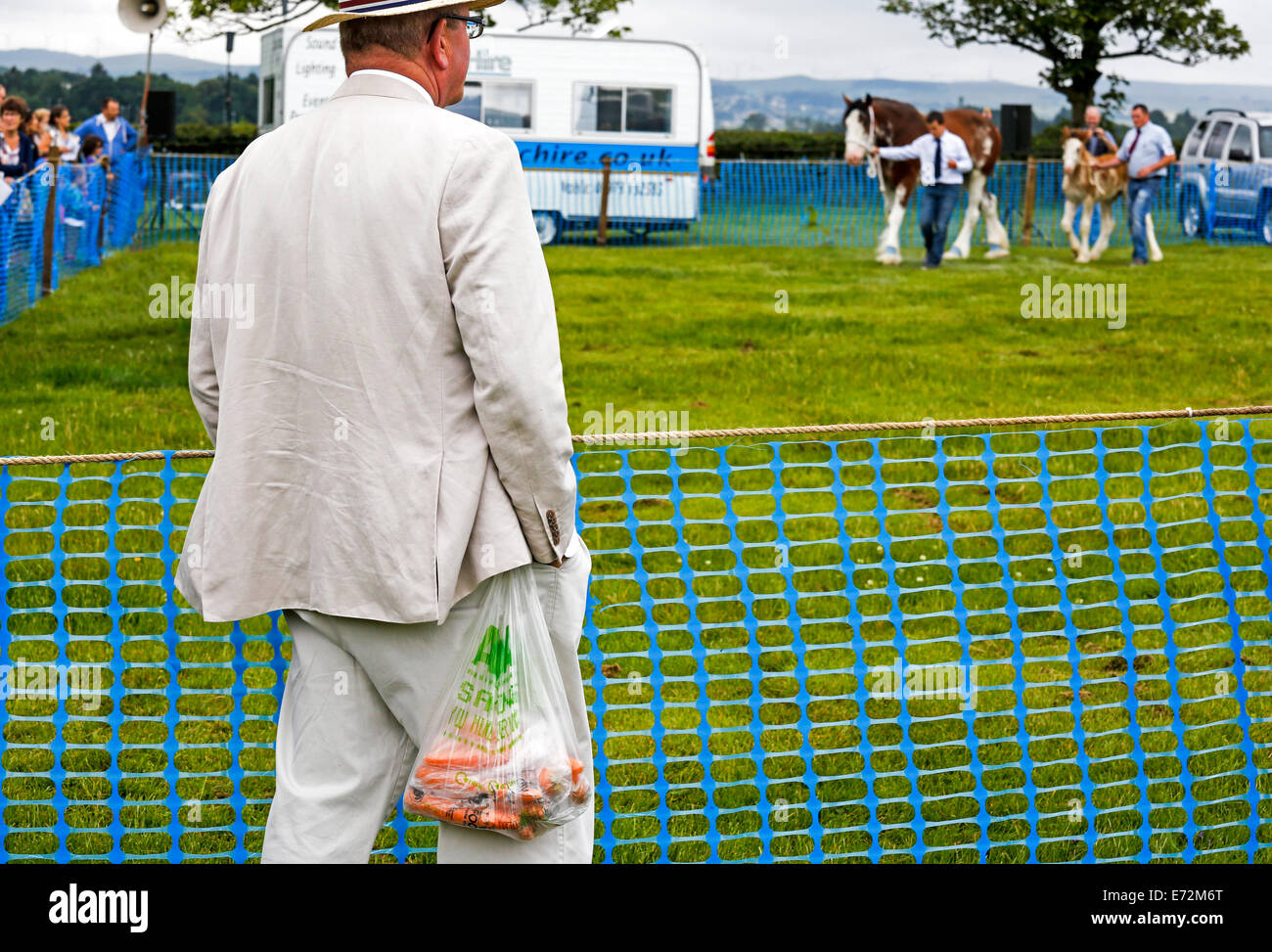 Uomo con un sacchetto di carote guardando uno spettacolo di cavalli in un paese equo, vicino a Glasgow, Scotland, Regno Unito Foto Stock