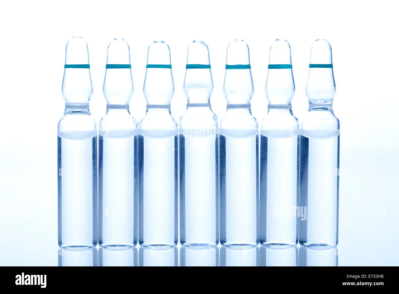 Medicina di vetro Ampolle con il liquido su un bianco e sfondo blu Foto Stock