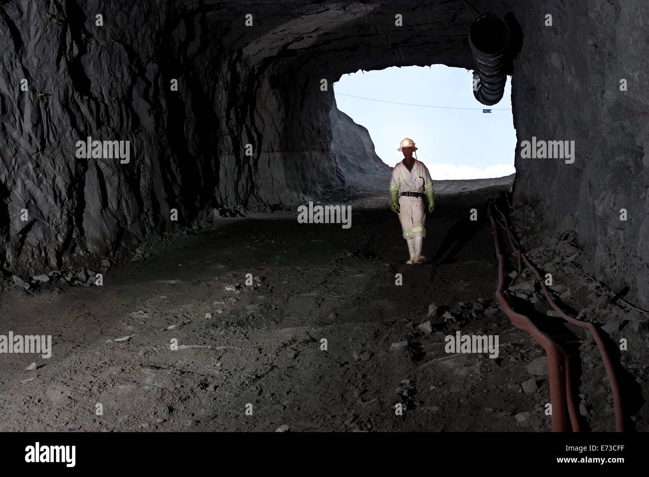 Minatore africano che cammina lungo il pendio per controllare l'accesso al tunnel di servizio nella nuova miniera sotterranea di platino - dal portale di ingresso dell'albero della rampa. Sudafrica Foto Stock