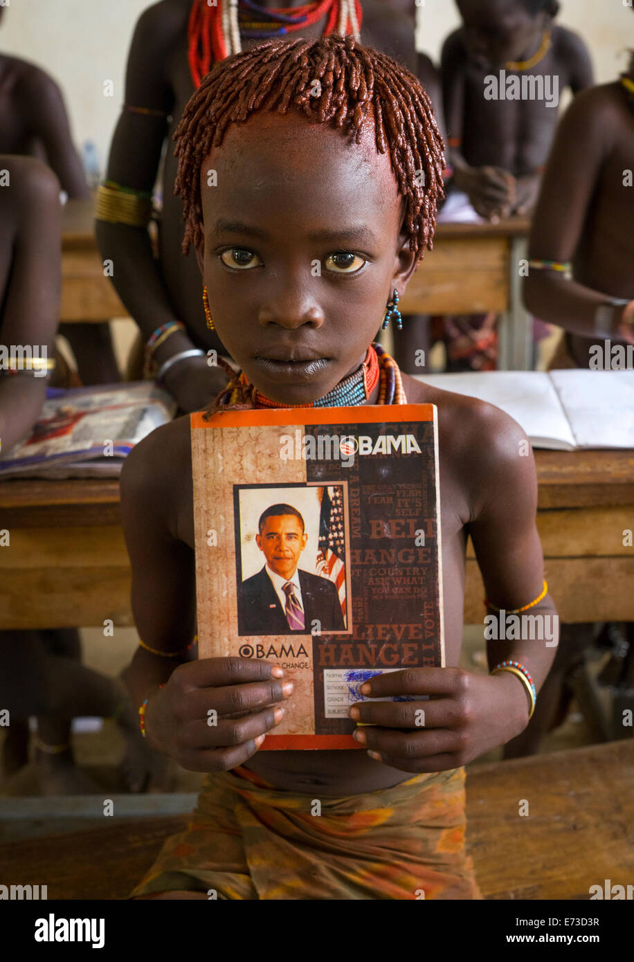 Hamer tribù ragazza in possesso di un libro con Barack Obama sul coperchio in una scuola, Turmi, Valle dell'Omo, Etiopia Foto Stock