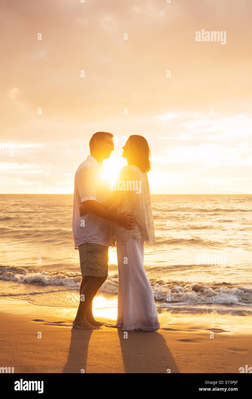 Romantico Coppia matura il bacio al tramonto sulla spiaggia Foto Stock