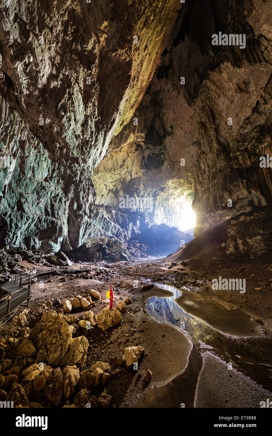 Persona in piedi nella grotta di cervi, Parco Nazionale di Gunung Mulu, Malaysia, passaggio più grande nel mondo (2° persona in distanza per la scala) Foto Stock