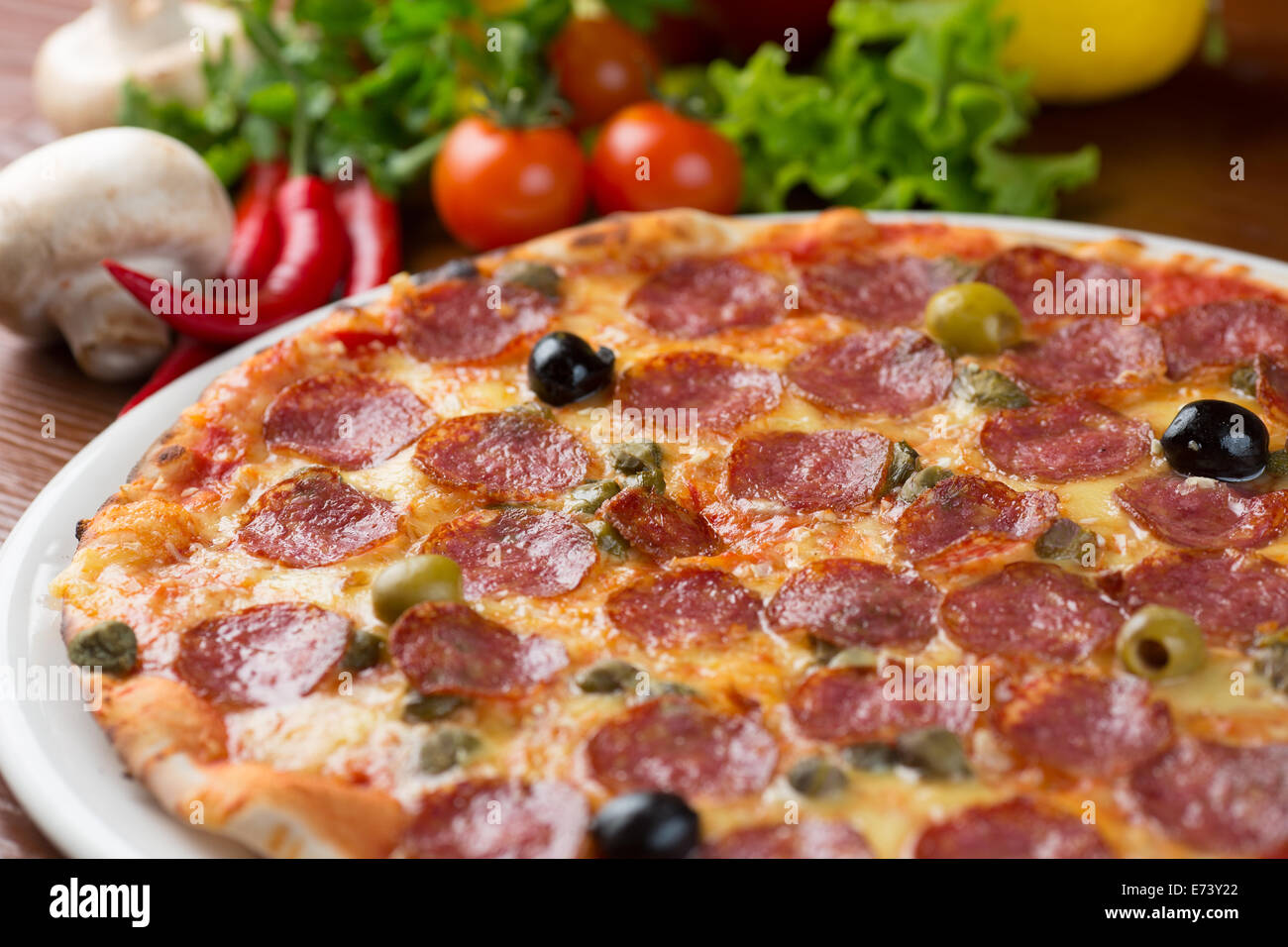 Salame pizza sul tavolo con verdure Foto Stock