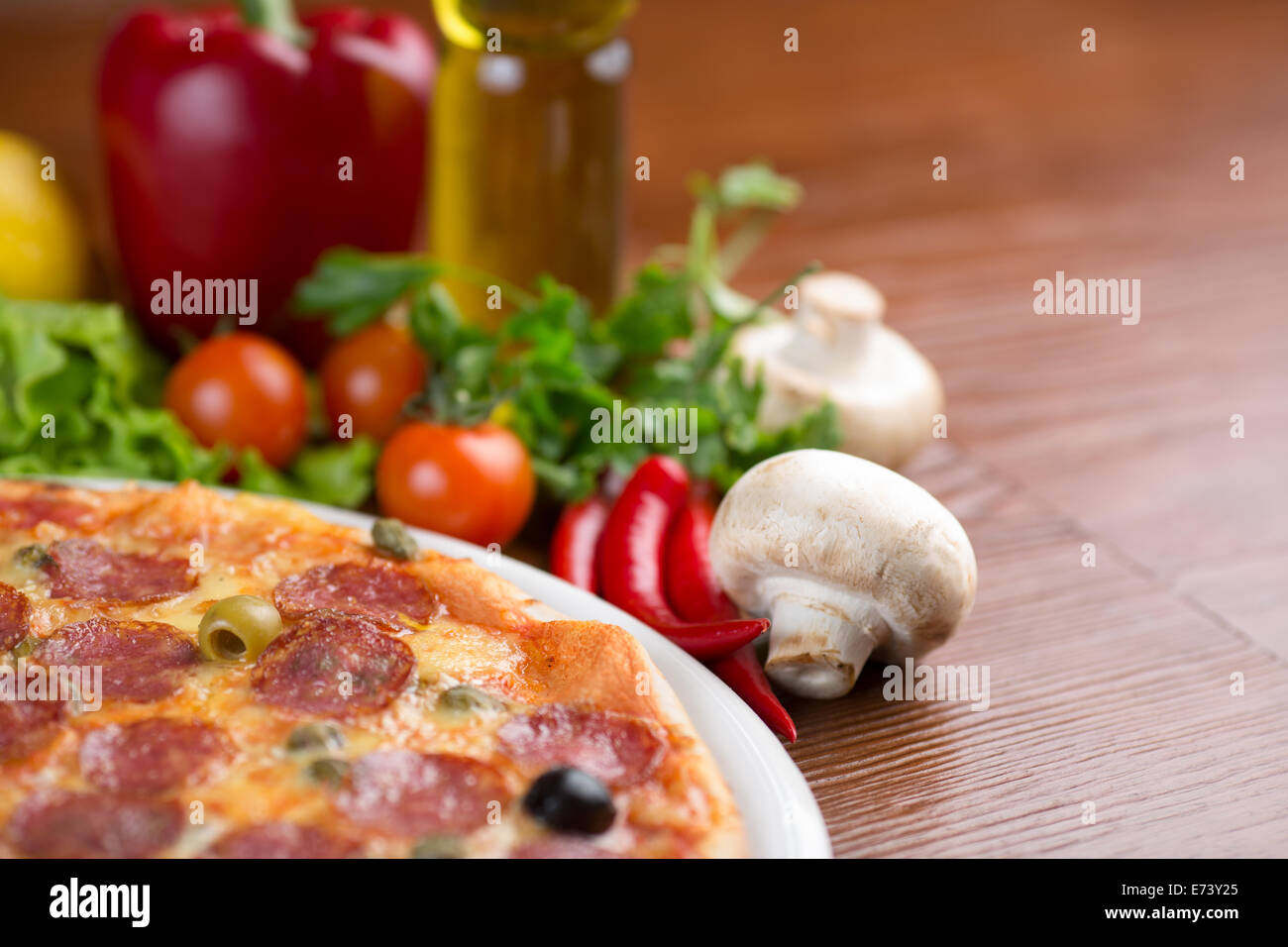 Salame pizza sul tavolo con verdure e stanza vuota Foto Stock