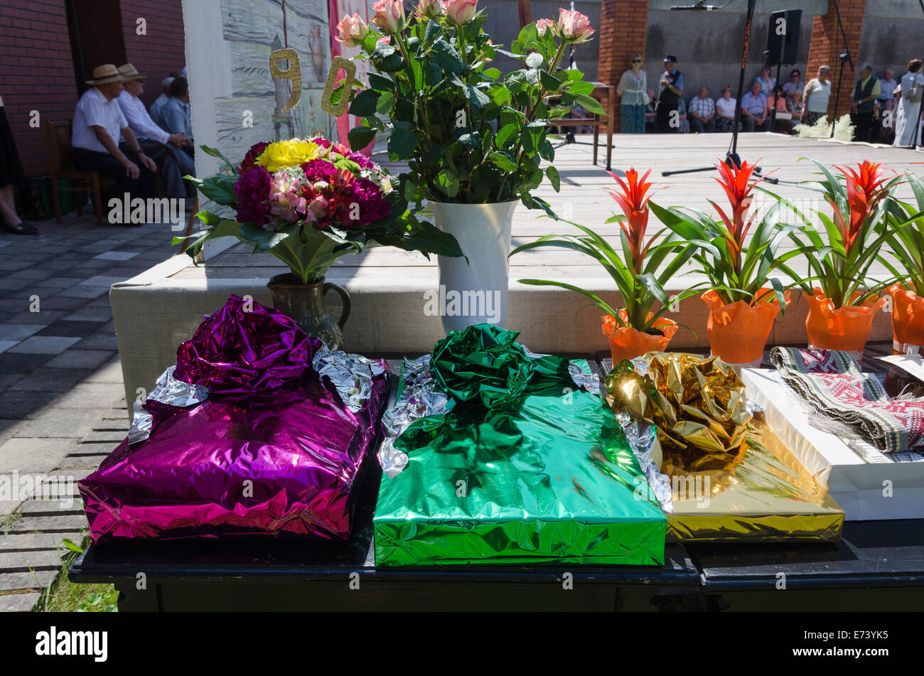 Regalo in carta lucida e fiore bouquet di rose e pentole in tavola Città evento festival all'aperto Foto Stock