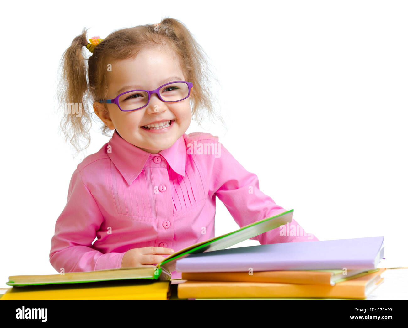 Bambino felice ragazza con gli occhiali lettura di libri seduta a tavola Foto Stock