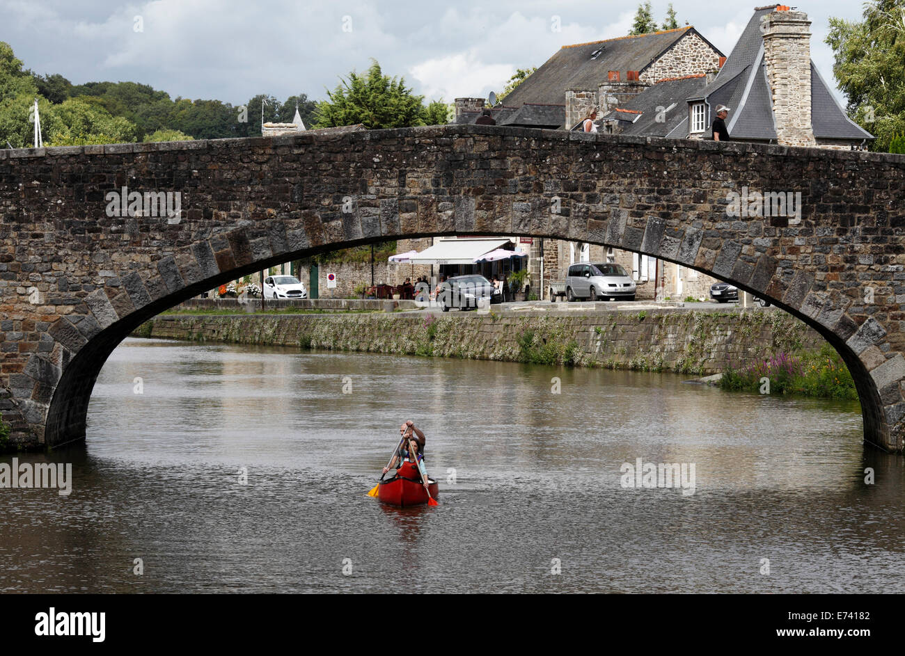 Due persone canoa sotto un ponte arcuato al porto di Dinan, Francia Foto Stock